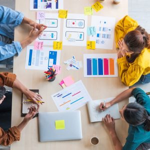 Top view ux developer and ui designer brainstorming about mobile app interface wireframe design on table with customer breif and color code at modern office.Creative digital development agency